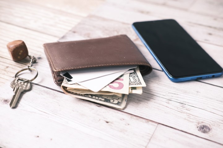 money in brown wallet next to cellphone