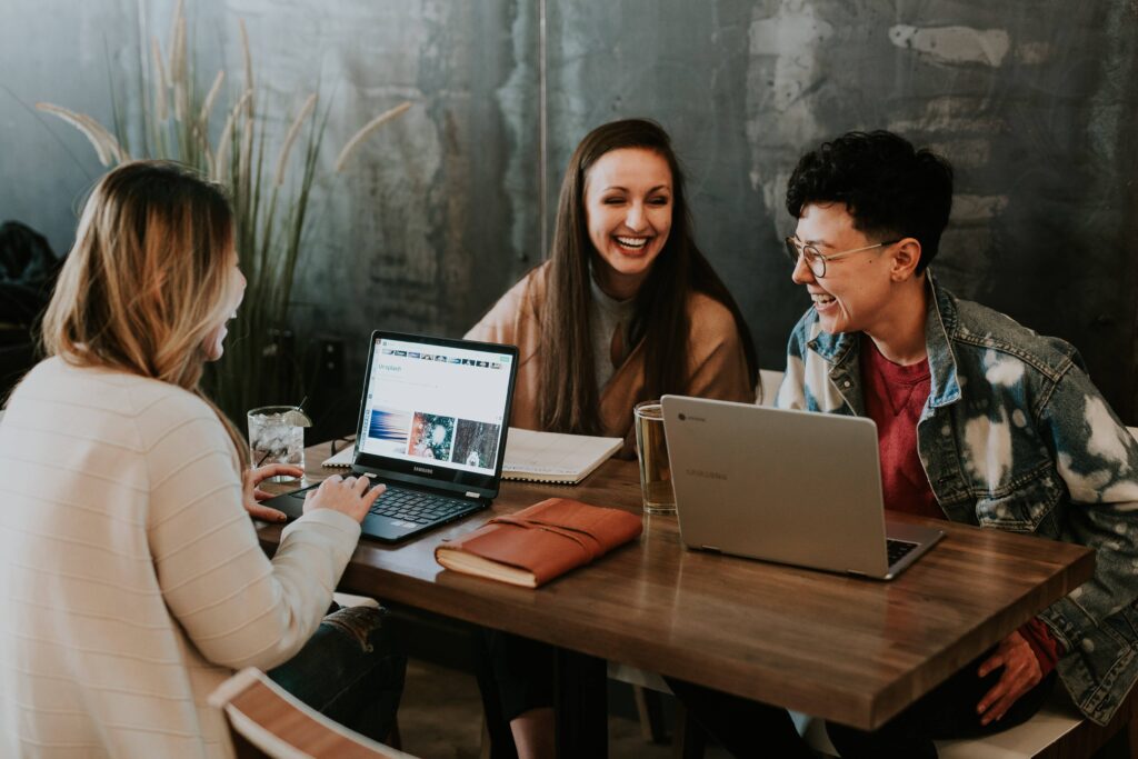 three students on laptops laughing while they work