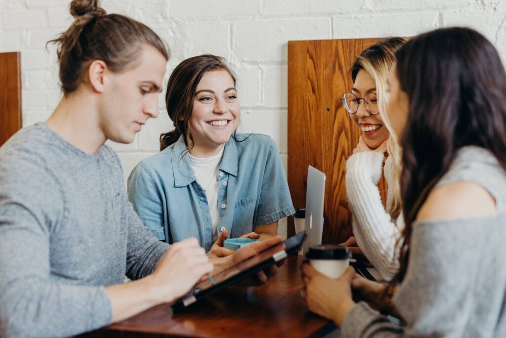 four students sitting with laptops and coffee