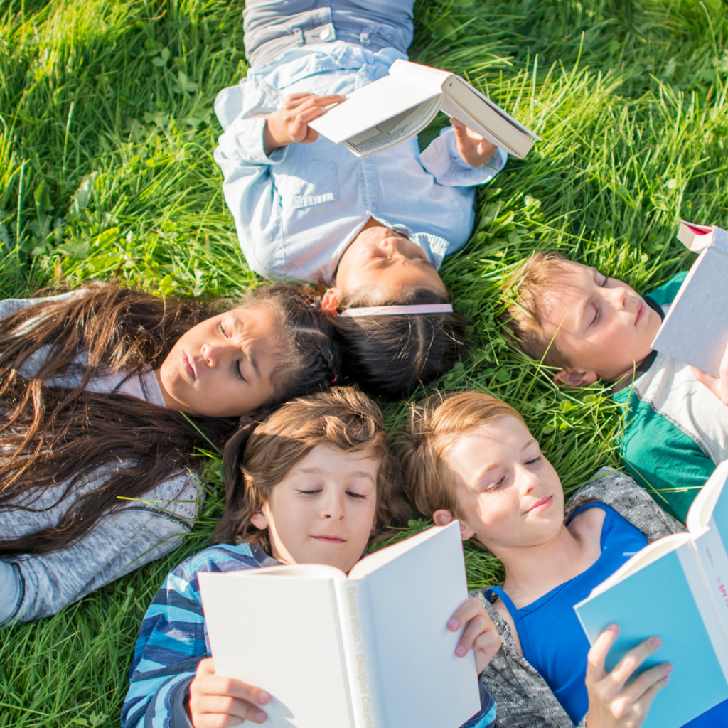 Five kids reading while laying in the grass