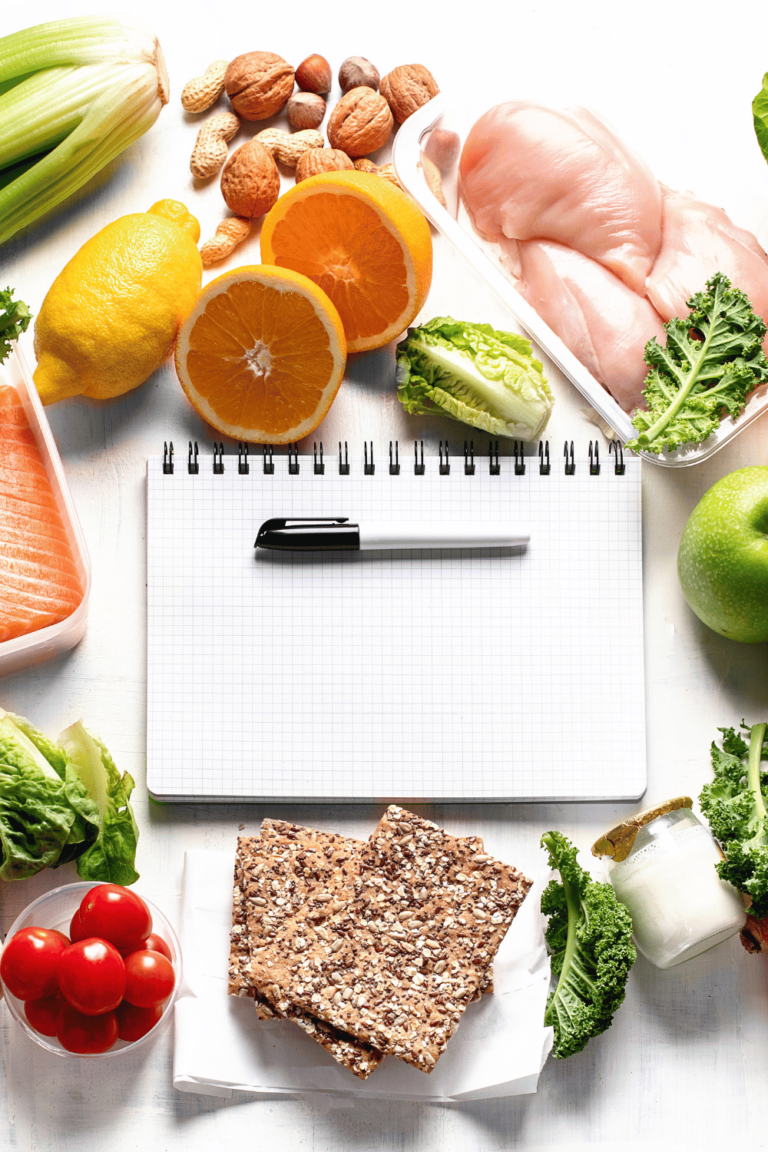 notebook and pen surrounded by ingredients for meal planning