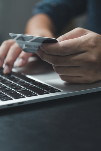 person holding credit card while typing on computer