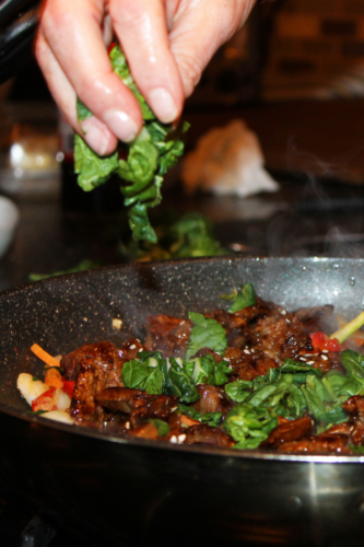 bok choy and beef cooking in a pan