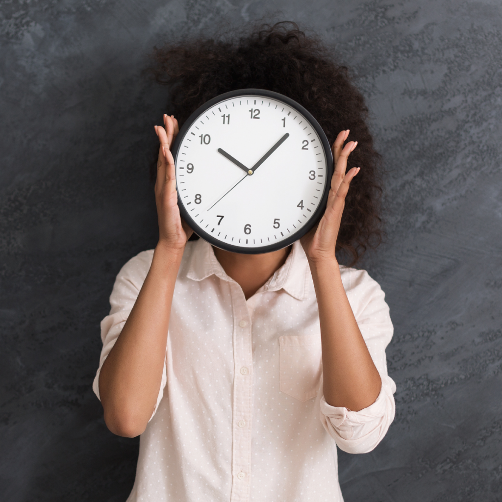 woman holding a clock in front of her face