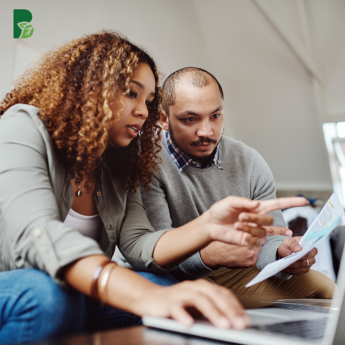 woman and man reading paper and looking at computer talking