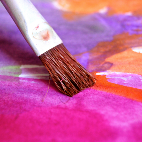 paint brush on canvas with pink, orange and purple paint