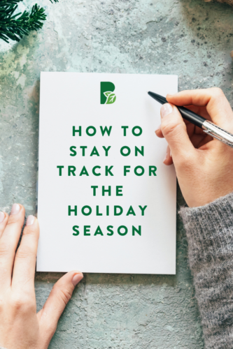 blank paper with Christmas tree sprigs and wrapping. text on paper reads "How to stay on track for the holiday season"