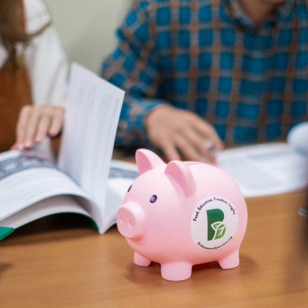 piggy bank in front of couple looking through financial literacy books