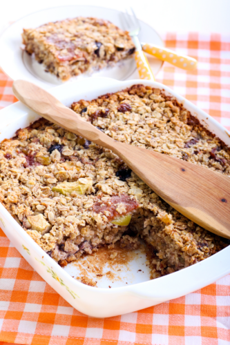 baked oatmeal in a square pan with a wood spoon on top