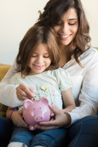 woman and child place coin in piggy bank, smiling together