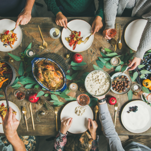 people sitting around holiday decorated table with chicken and other dishes