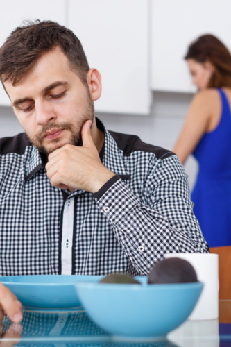 man looking at empty blue bowl with his partner behind him