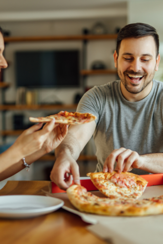 couple eating pizza at their kitchen table
